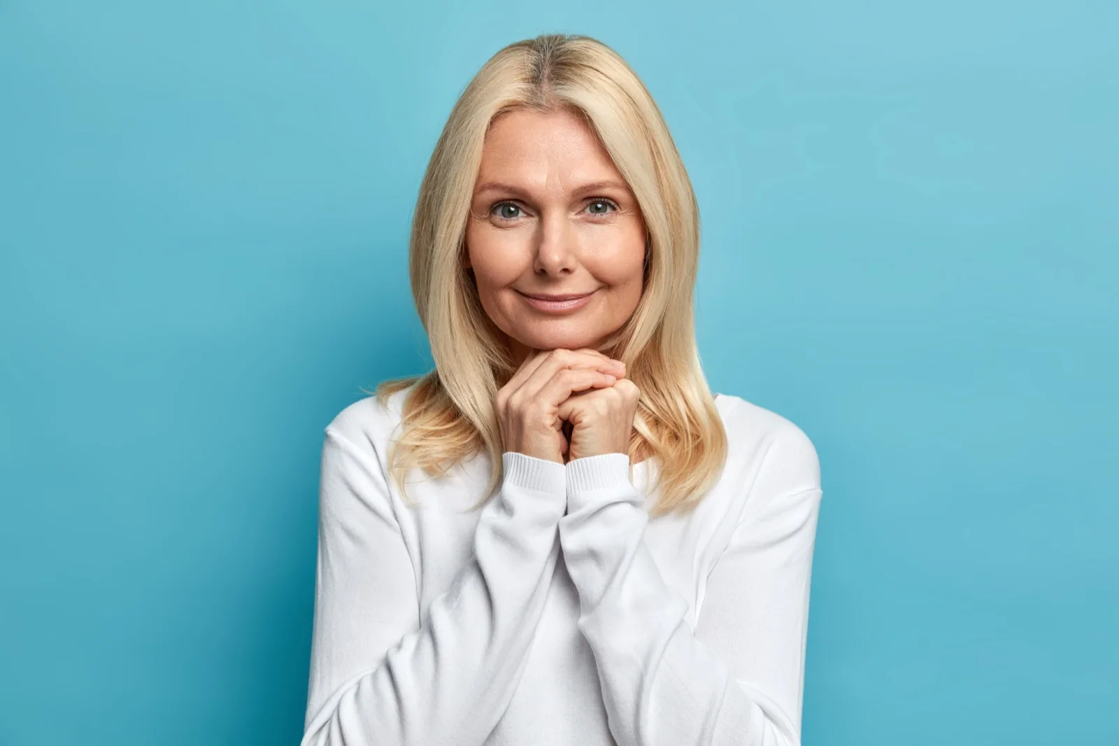 Frau um die 50 mit ruhigem Blick, die Hände am Kinn